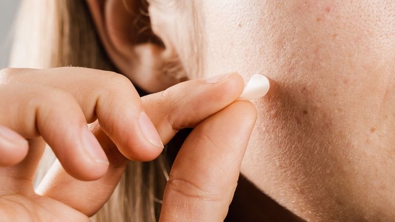 woman applying a pimple patch