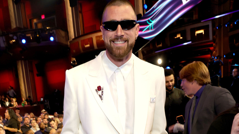 Travis Kelce in a white suit with sunglasses