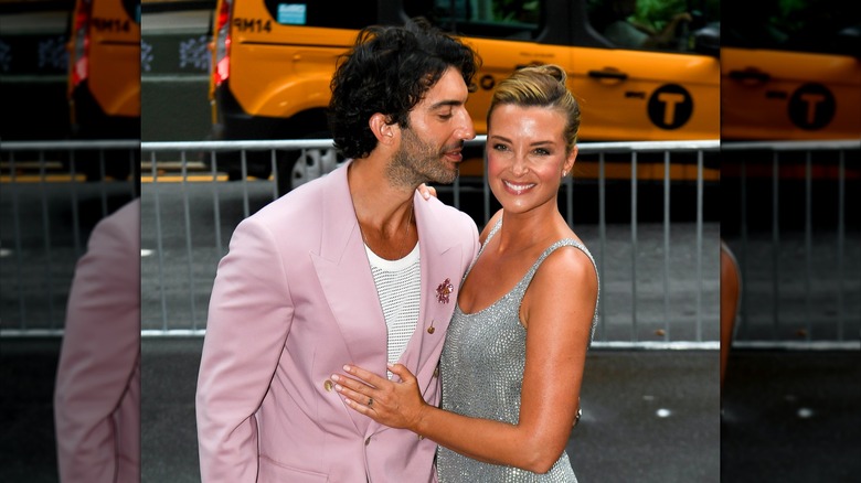 Justin Baldoni leaning in to kiss his wife, Emily, while she poses for photos.