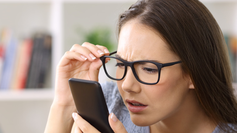 woman with glasses holding phone