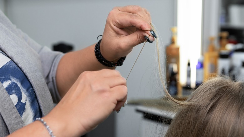 stylist stretching client's hair
