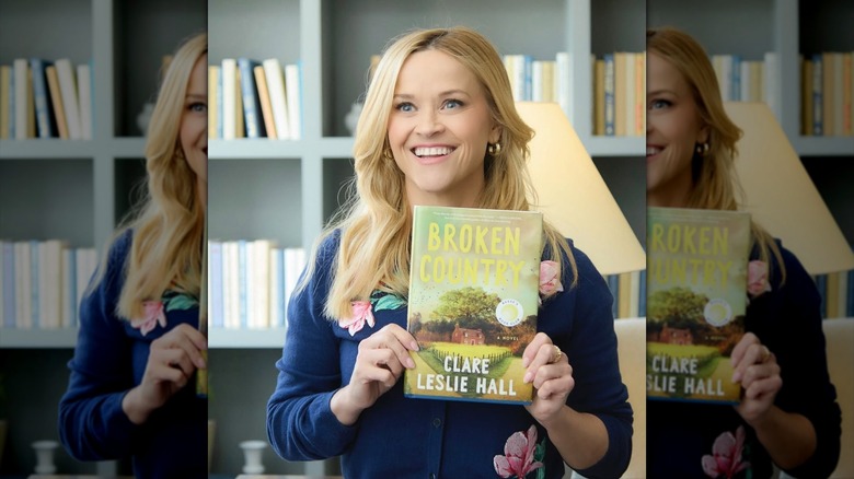 Reese Witherspoon holding up "Broken Country" by Clare Leslie Hall