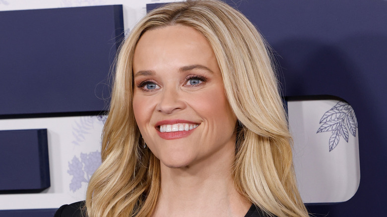 Reese Witherspoon posing in black while wearing pink lipstick