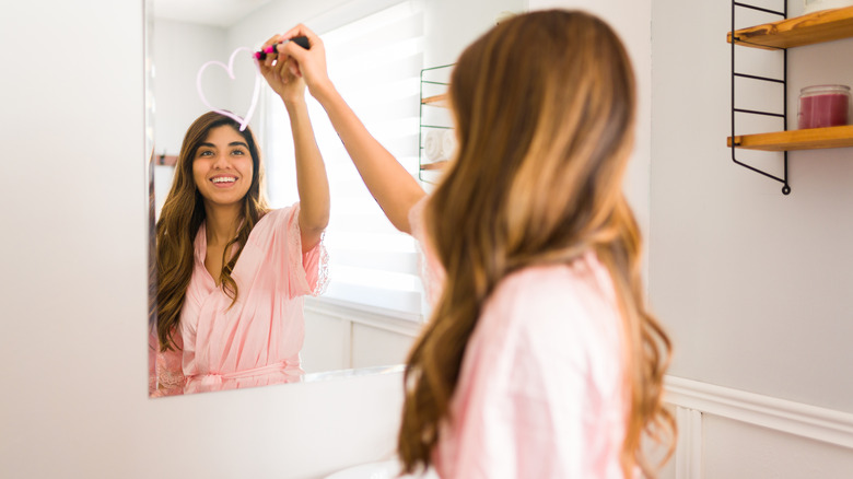 A women drawing a heart in the mirror