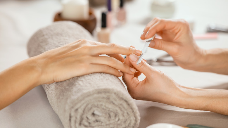 shot of woman getting nail filed at salon
