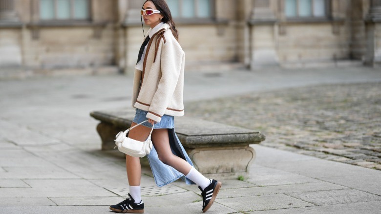 Woman wearing skirt, jacket, Adidas