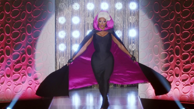 RuPaul in a jumpsuit and a cape