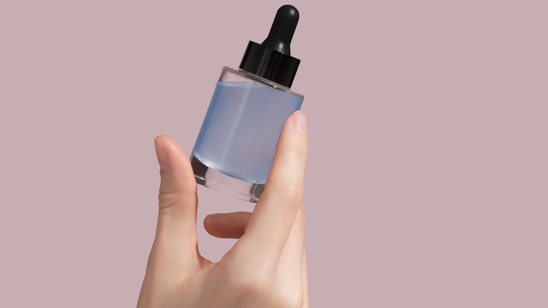 woman holding a bottle of scalp serum