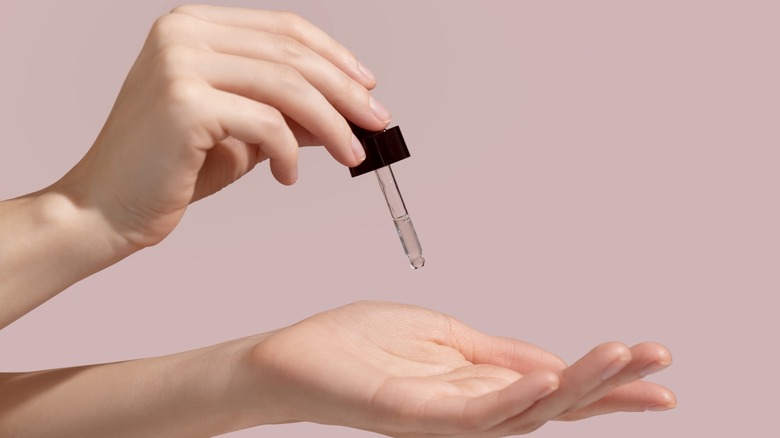 woman dropping scalp serum into hand