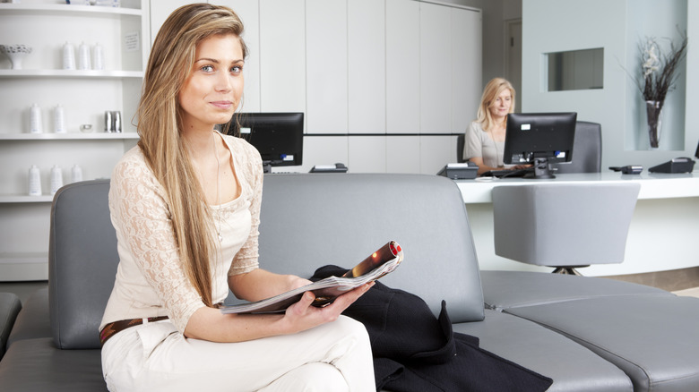 A woman waiting and reading a magazine at a salon.