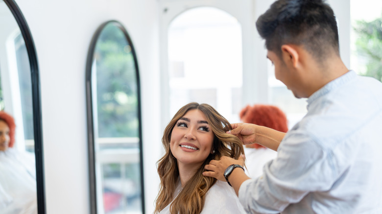 A client smiling and talking to the hairstylist while the stylist does her hair.