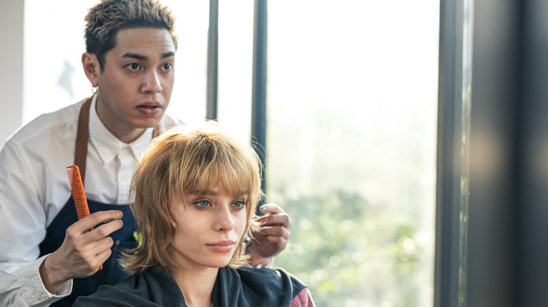 A client sitting in the salon chair looking into the mirror with a stylist behind them.