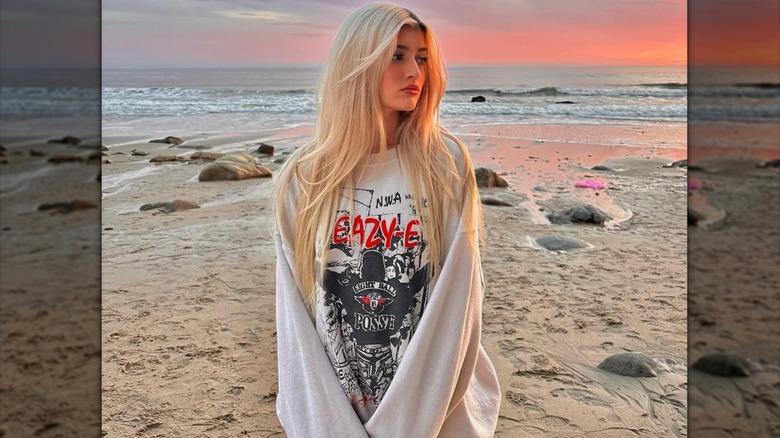 Sami Sheen posing on the beach with platinum hair and dark roots