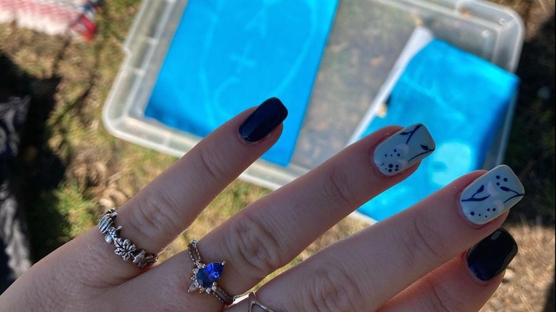 Hand displaying small sapphire engagement ring 