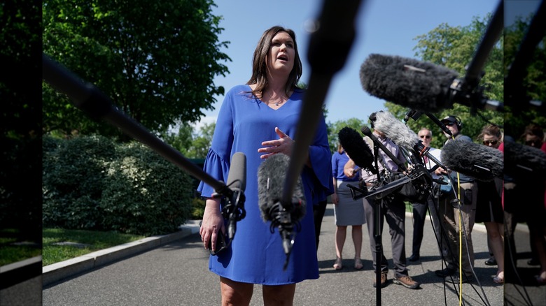 Sarah Huckabee Sanders speaks to reporters in a blue shift dress with bell sleeves