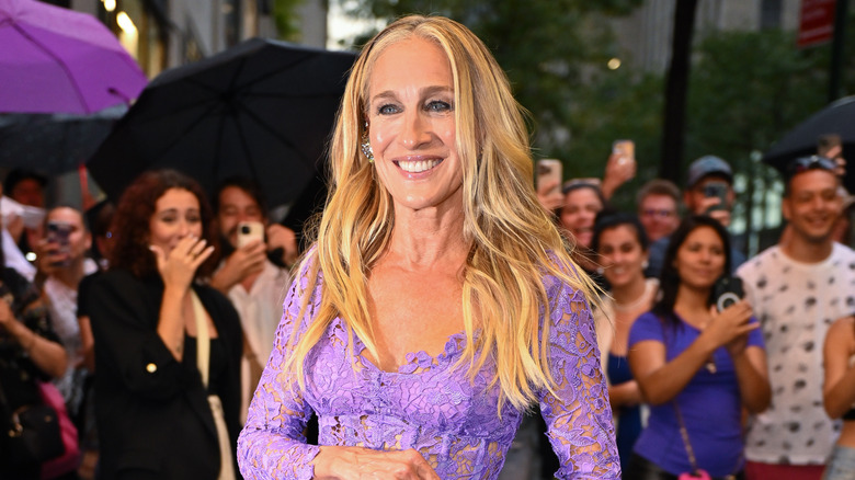 Sarah Jessica Parker posing at an event in a purple lace dress.