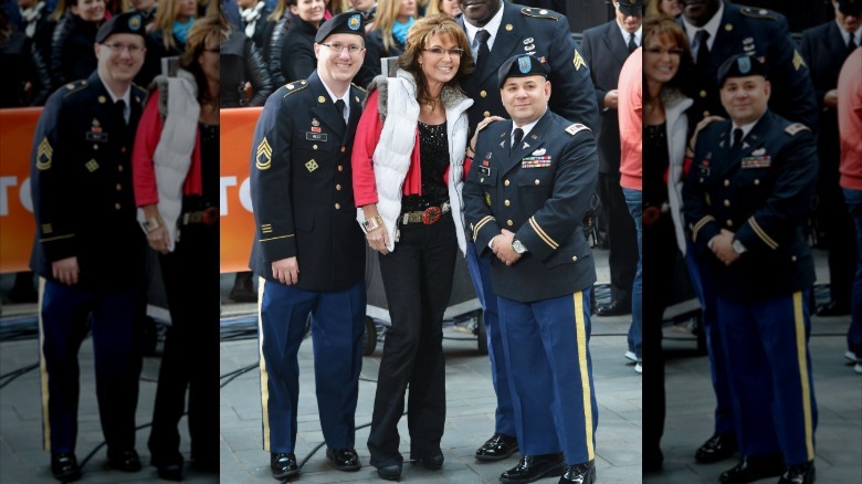 Sarah Palin smiles with two officers while wearing a puffer vest