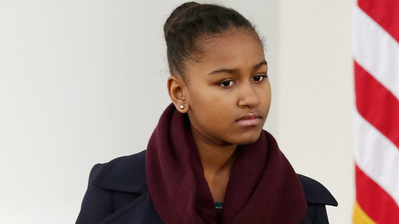 Sasha Obama walking in a blue top and a bun
