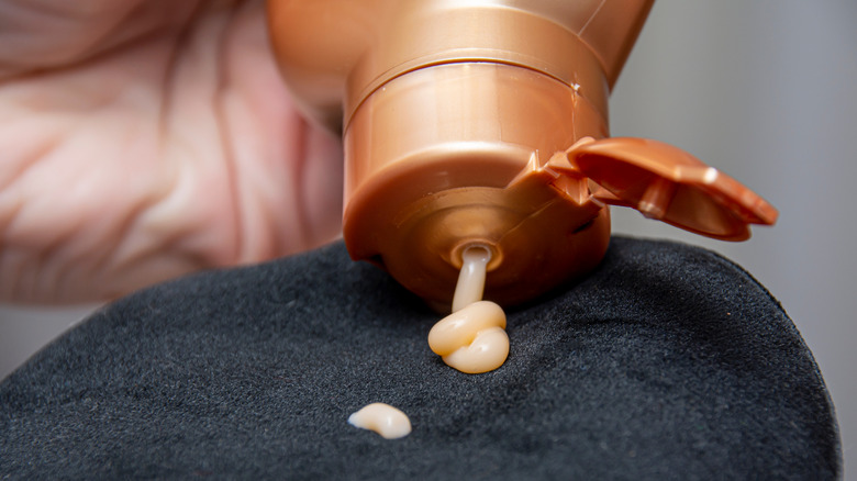 woman squeezing tanner onto mitt