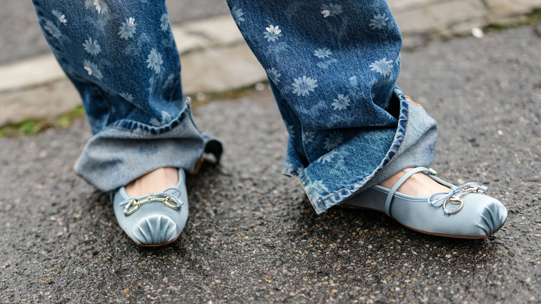 close up of blue satin ballet flats worn under baggy jeans