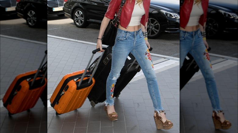 Woman outside airport pulling luggage