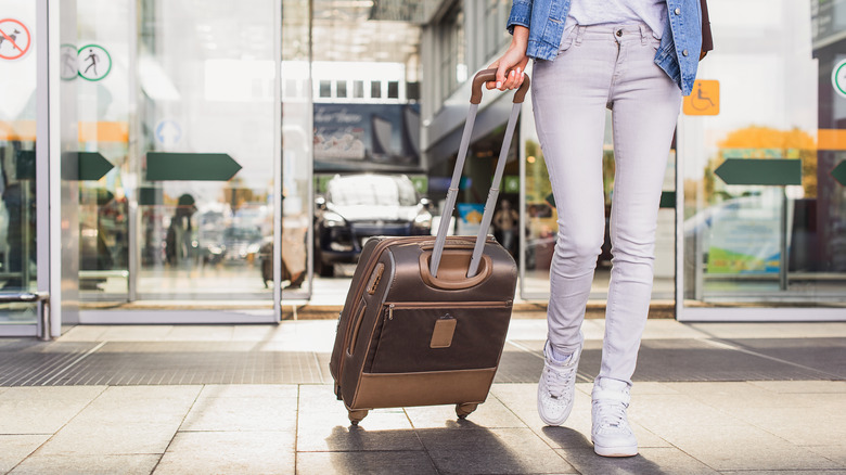 Woman entering airport pulling luggage