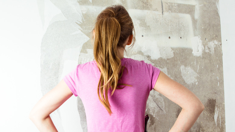 woman seeing peeling wallpaper