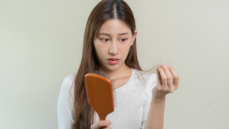 woman pulling hair from hairbrush