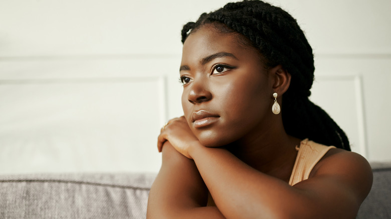 Woman sadly reflects on sofa