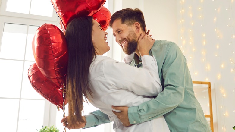 hugging couple with heart balloons