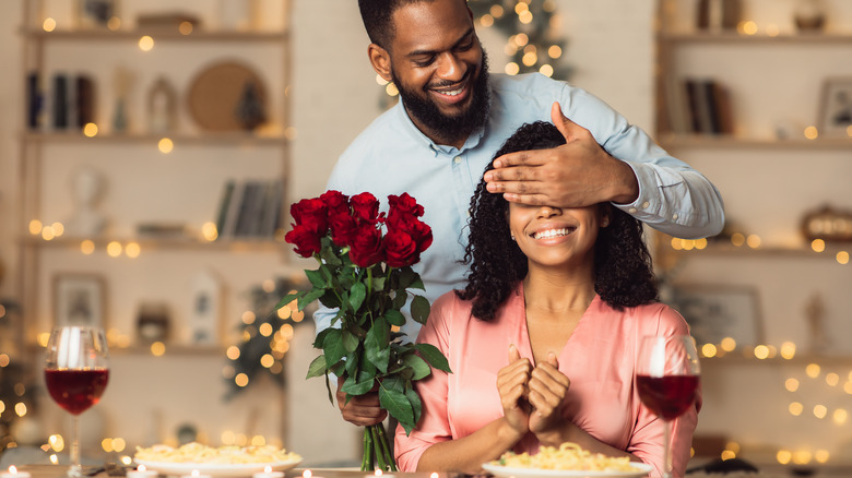 A man surprising a woman with dinner and flowers