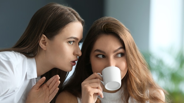 woman whispering to another woman