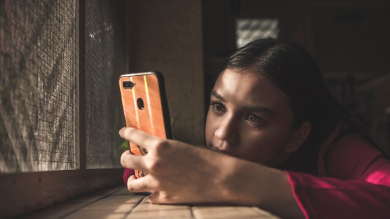 woman staring at her phone sad