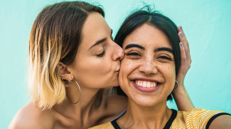 Smiling lesbian couple cheek kiss