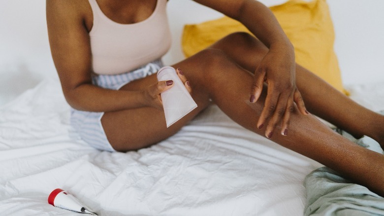 Woman applying lotion to legs