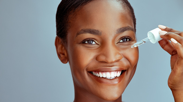 Woman applying skin serum to face