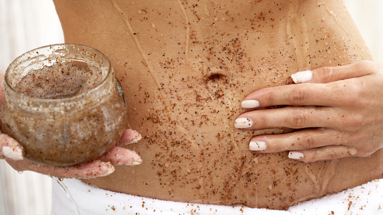 Woman exfoliates midriff with scrub