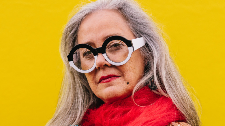 A mature woman wearing artsy eyeglasses with black-and-white frames.