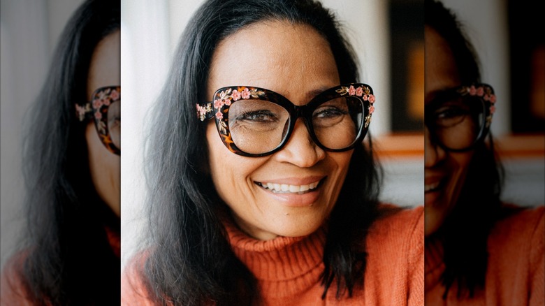 A mature woman wearing thick eyeglasses with floral embellishments.