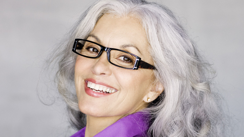 A mature woman wearing narrow, rectangular glasses.