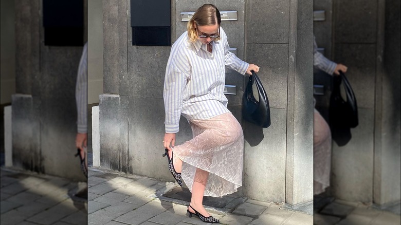 Woman wearing bottom down shirt over long lace slip dress with sling back shoes