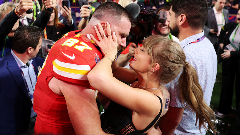 Taylor Swift holding Travis Kelce's face on the field