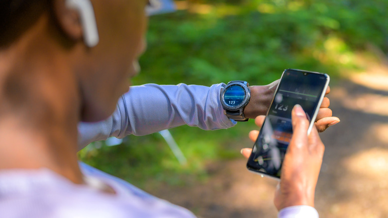 Woman checks her smartwatch and smartphone