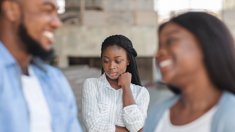 Upset person behind smiling couple