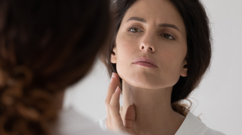 woman checks face in mirror