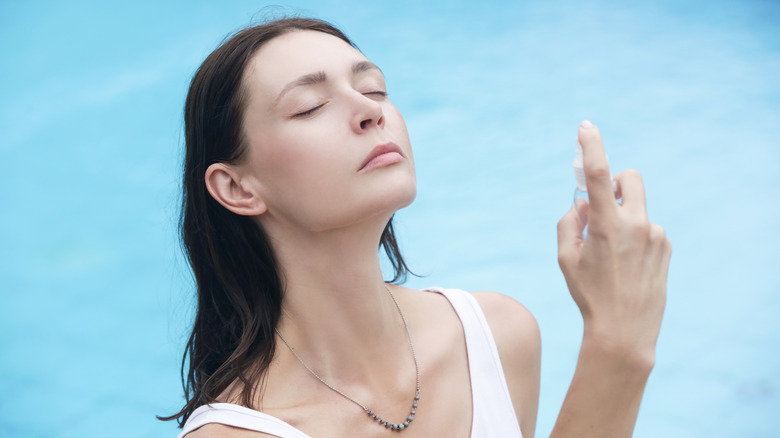 Woman misting on skincare in pool