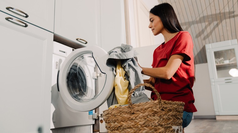 woman putting clothes in washing machine