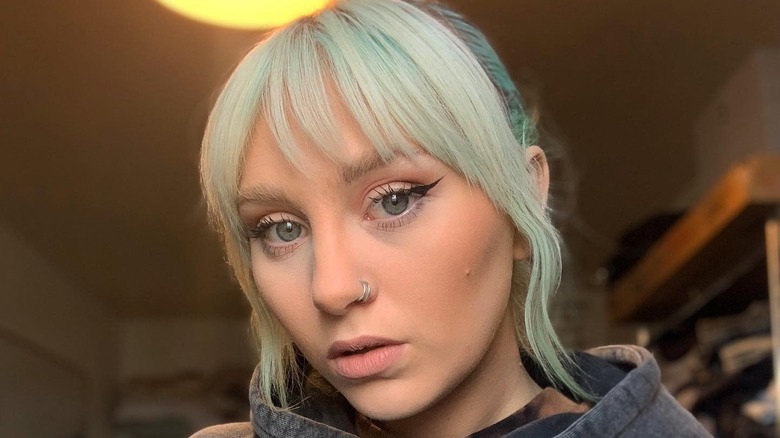 Two silver nostril hoop piercings