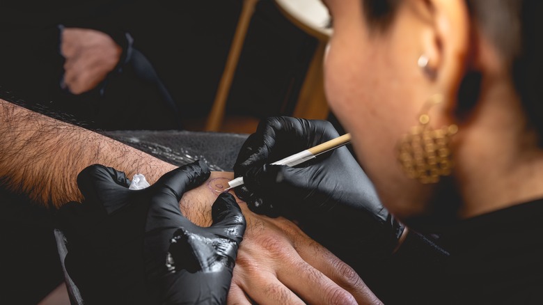 artist doing stick and poke tattoo