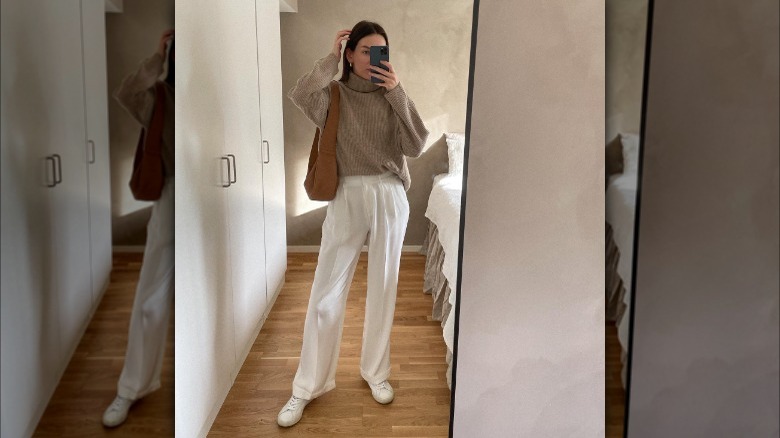 woman wearing white trousers and turtleneck sweater